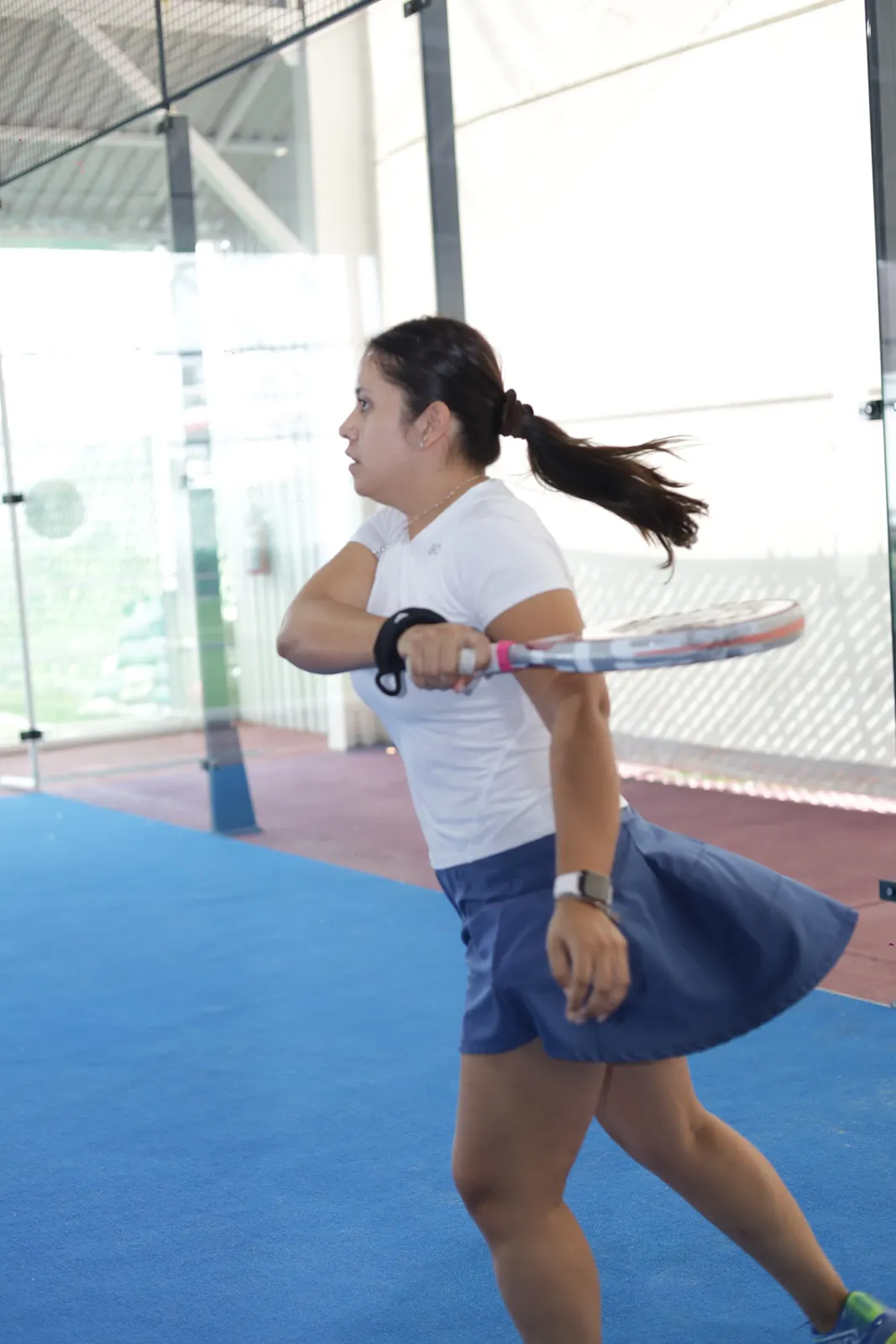 Jugadora pegando un drive en la cancha de pádel
